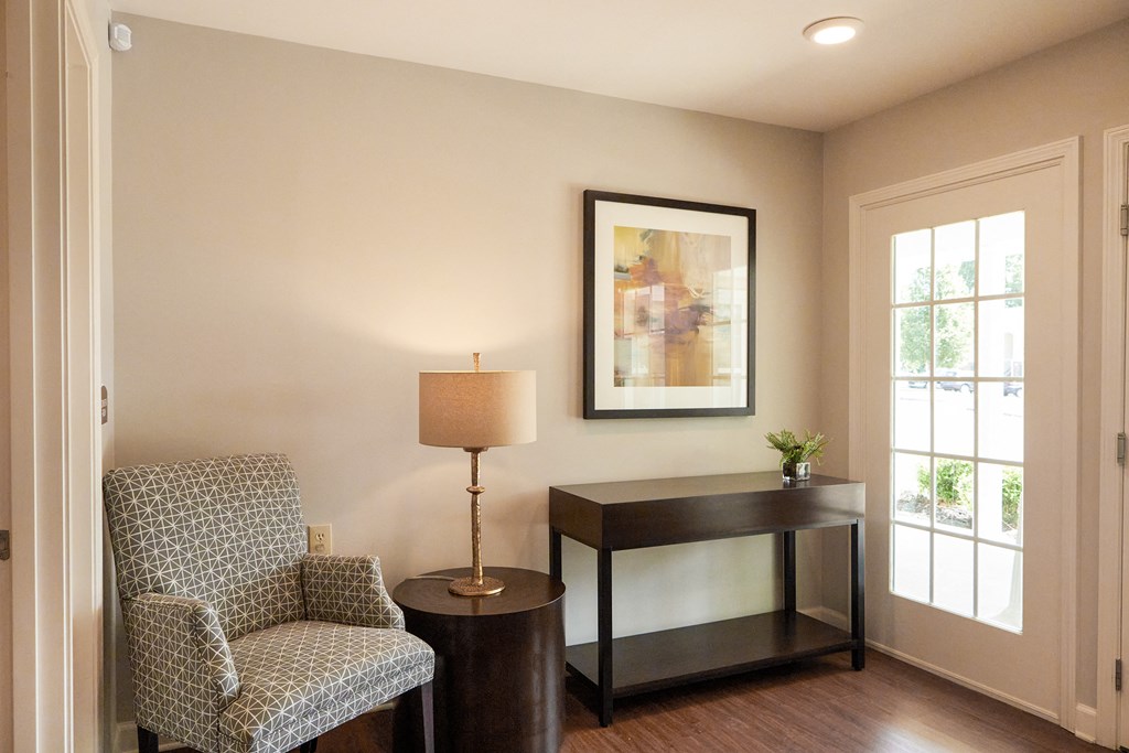 a living room with a chair and a table with a lamp