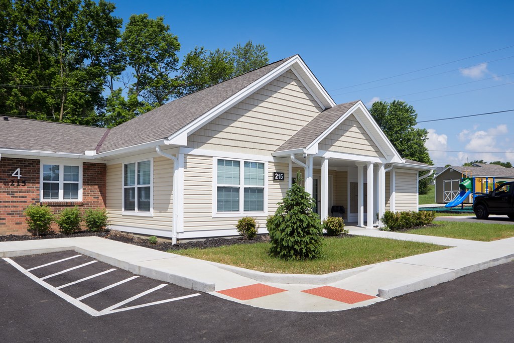 a white house with a lawn in front of a parking lot