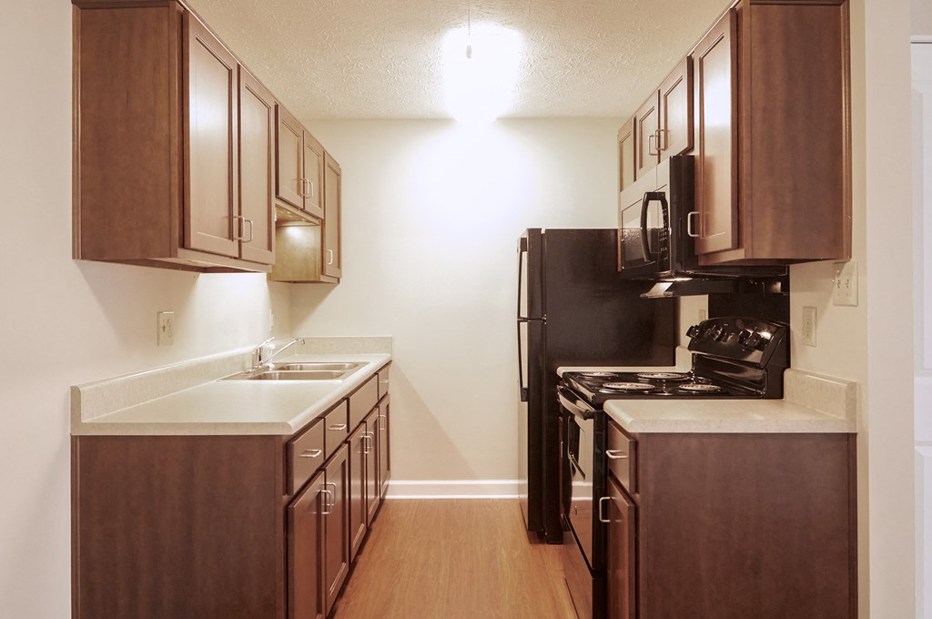 a kitchen with wooden cabinets and a black refrigerator