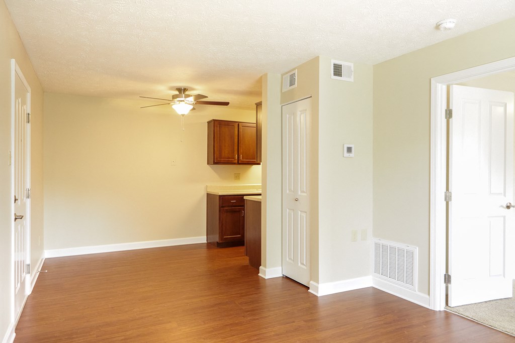 an empty living room and kitchen with a ceiling fan