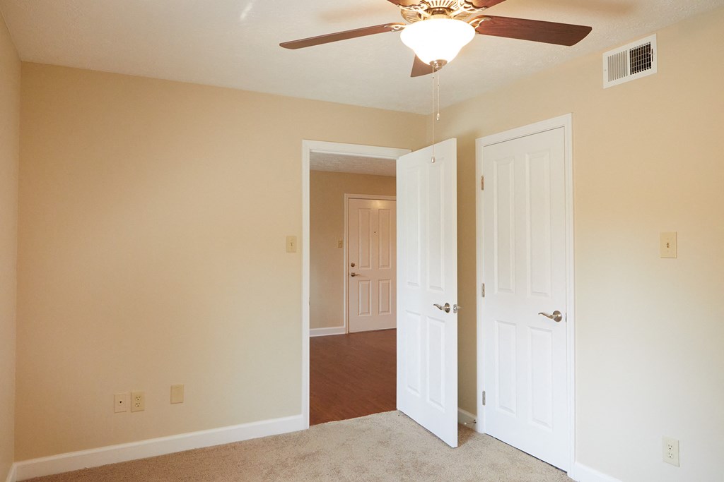 an empty living room with a ceiling fan and two doors