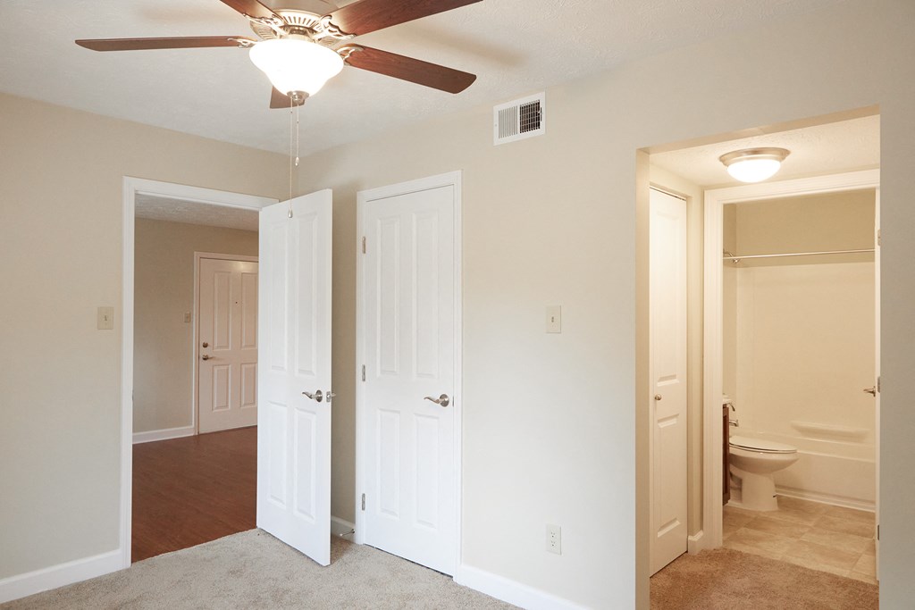 an empty living room with a ceiling fan and a bathroom