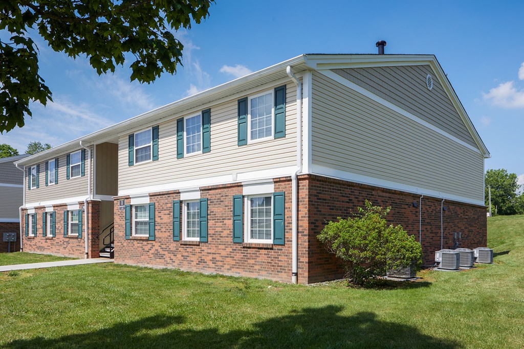a white house with green shutters and a lawn and a tree