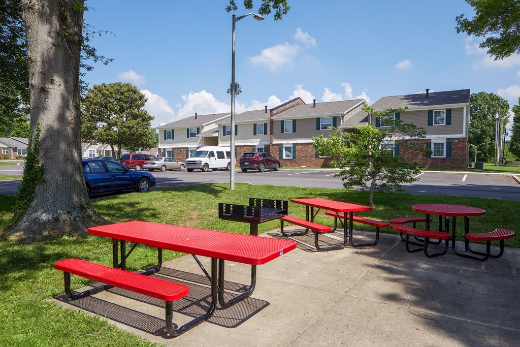 a group of picnic tables with benches on a sidewalk