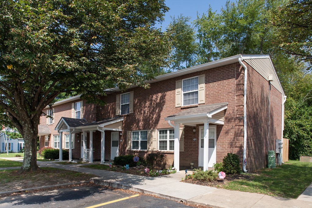 a red brick house with a tree in front of it
