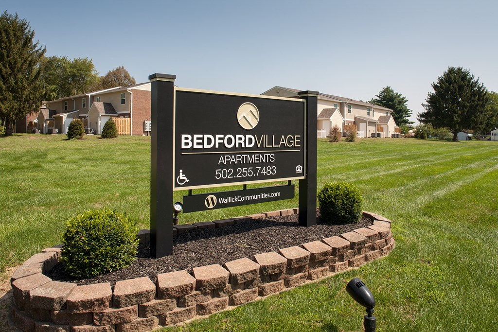 a sign apartments in front of a grass field