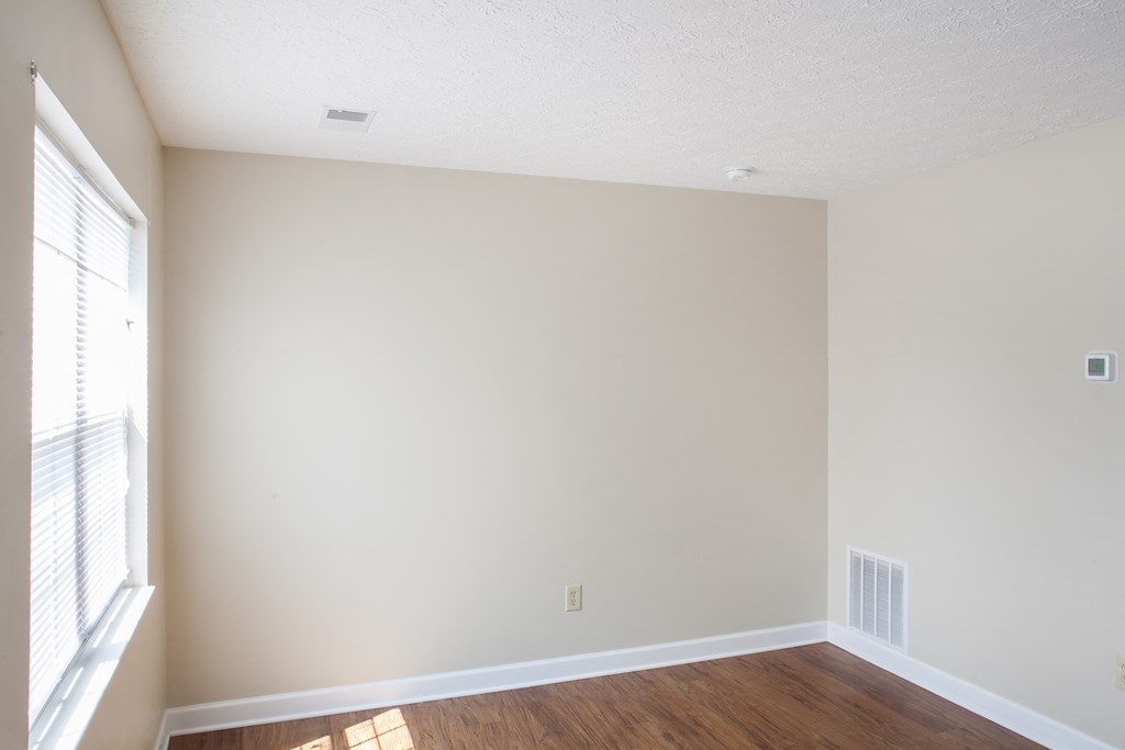 an empty living room with wood floors and a window