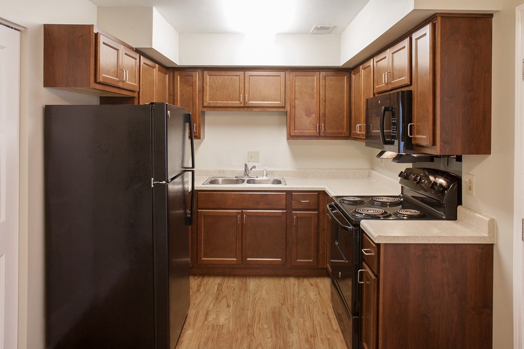a kitchen with wooden cabinets and a black refrigerator