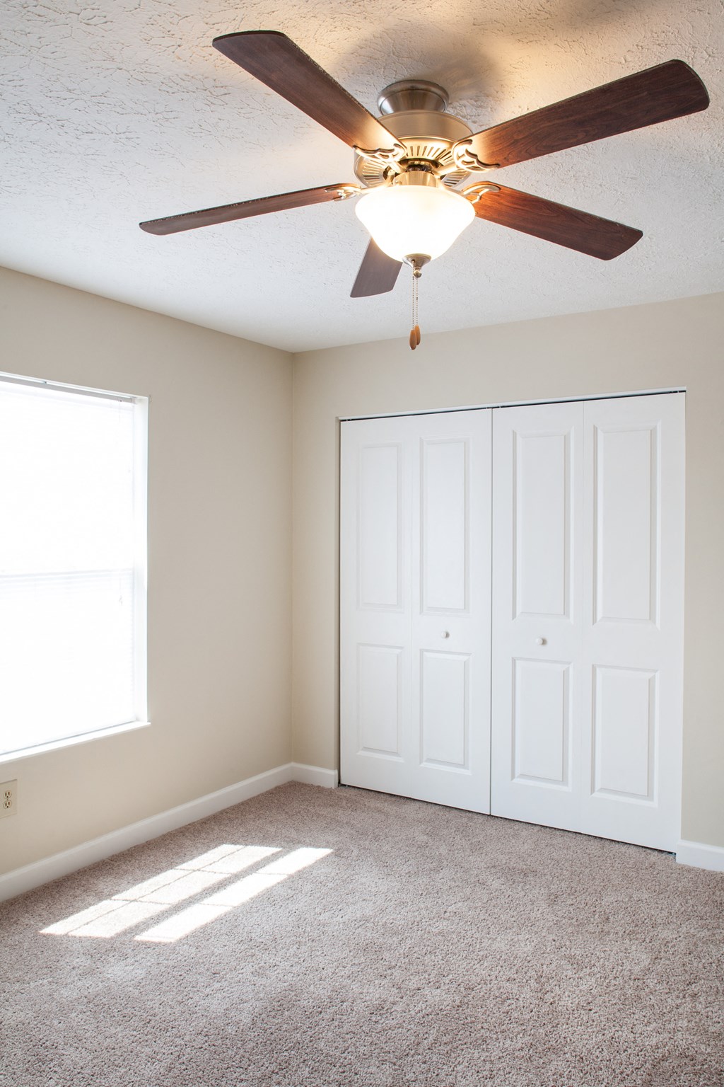 an empty room with a ceiling fan and a closet