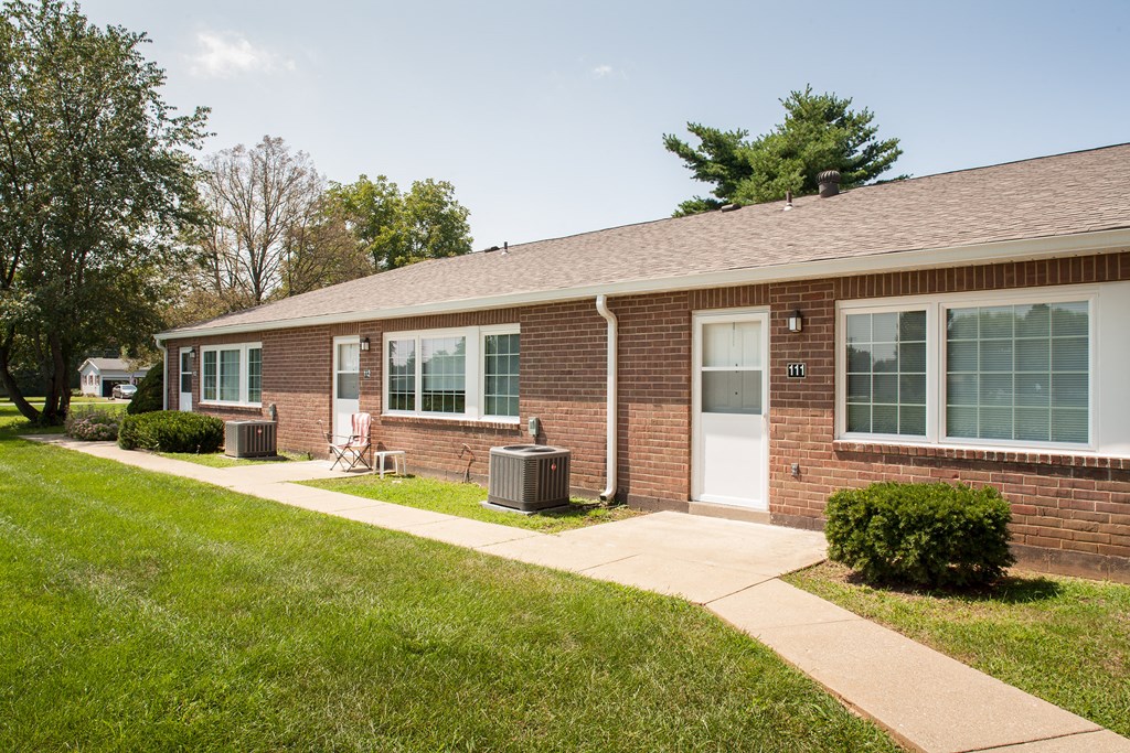 the front of a brick house with a sidewalk and grass