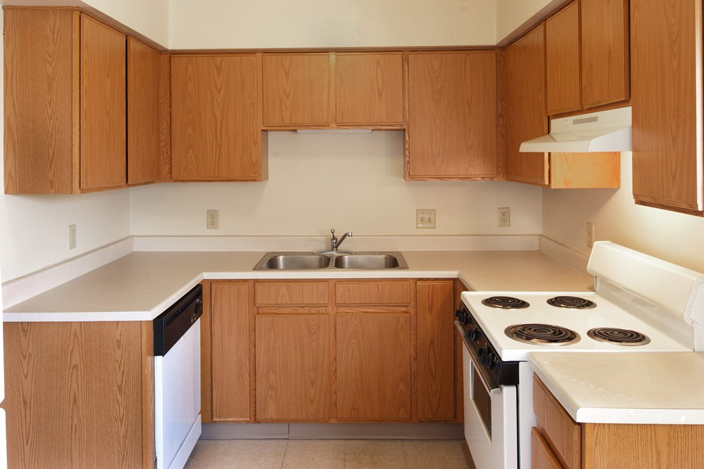 an empty kitchen with wooden cabinets and white appliances