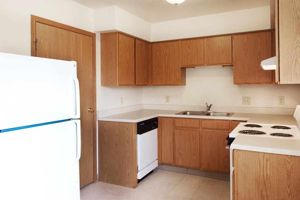 an empty kitchen with white appliances and wooden cabinets