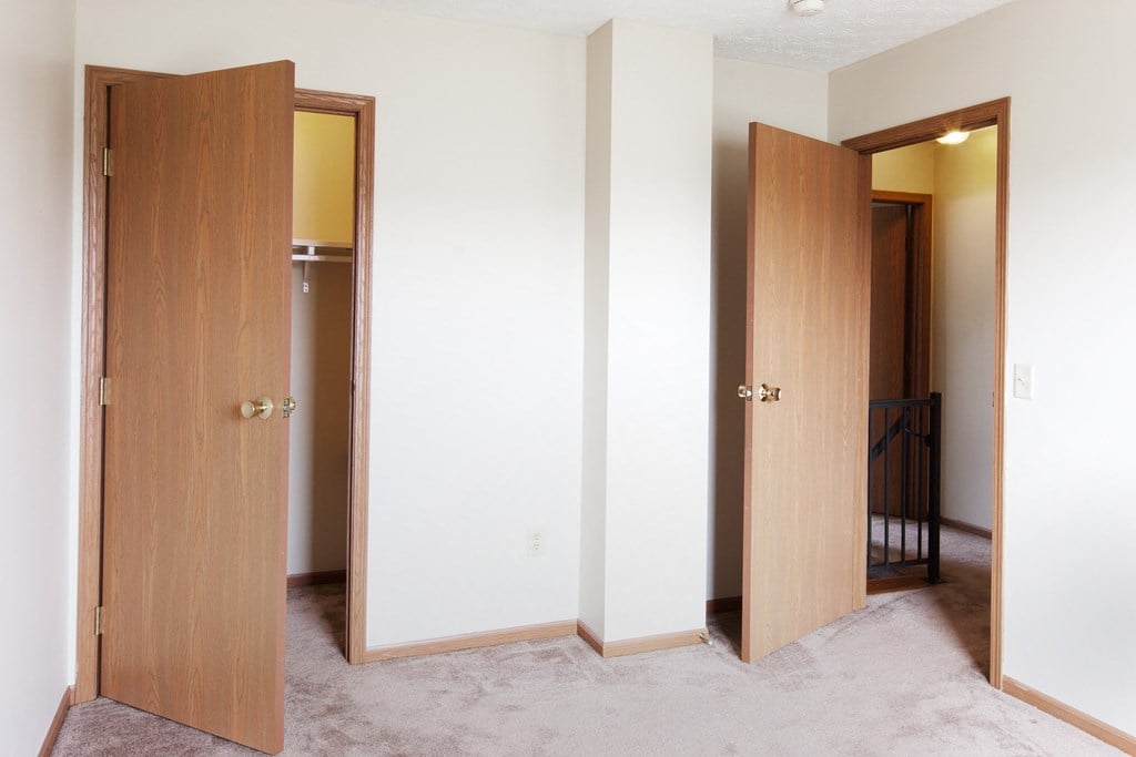 a bedroom with three doors and a hallway to a closet