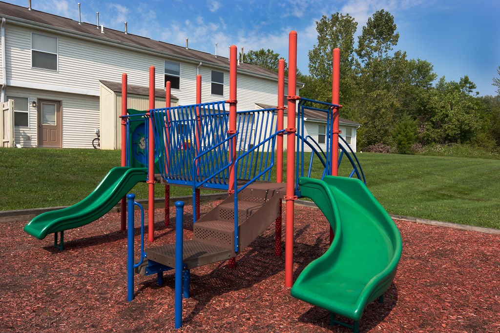 a playground with a slide and a staircase in front of a building