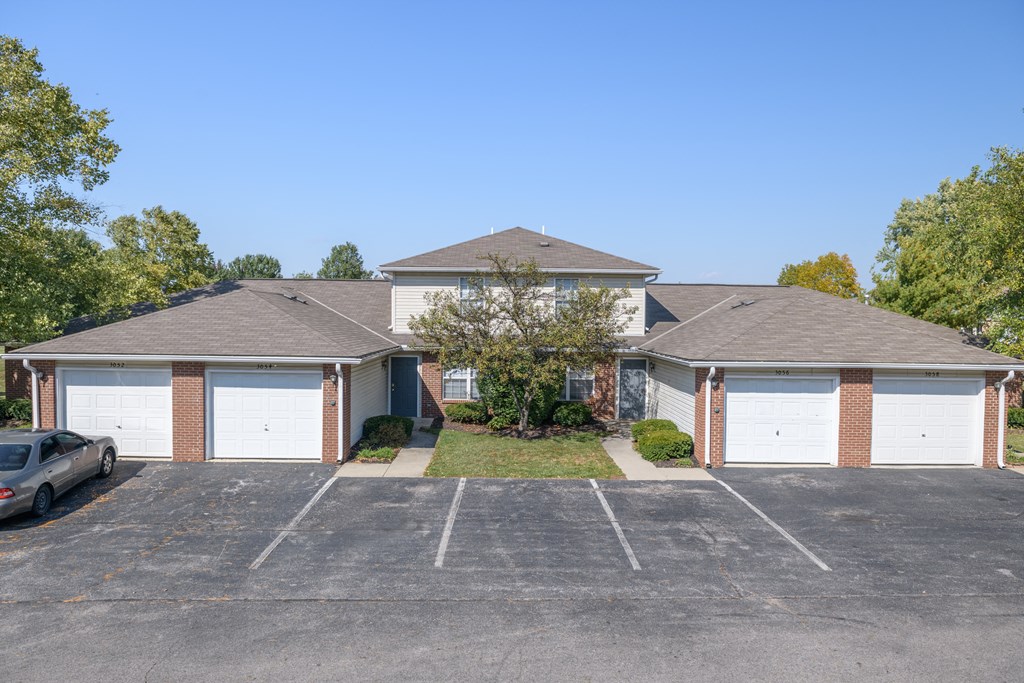 an empty parking lot in front of a house with garages