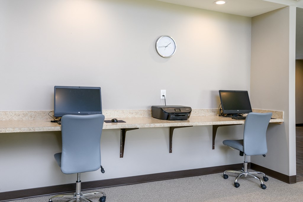 a office with two desks with computers and a clock on the wall