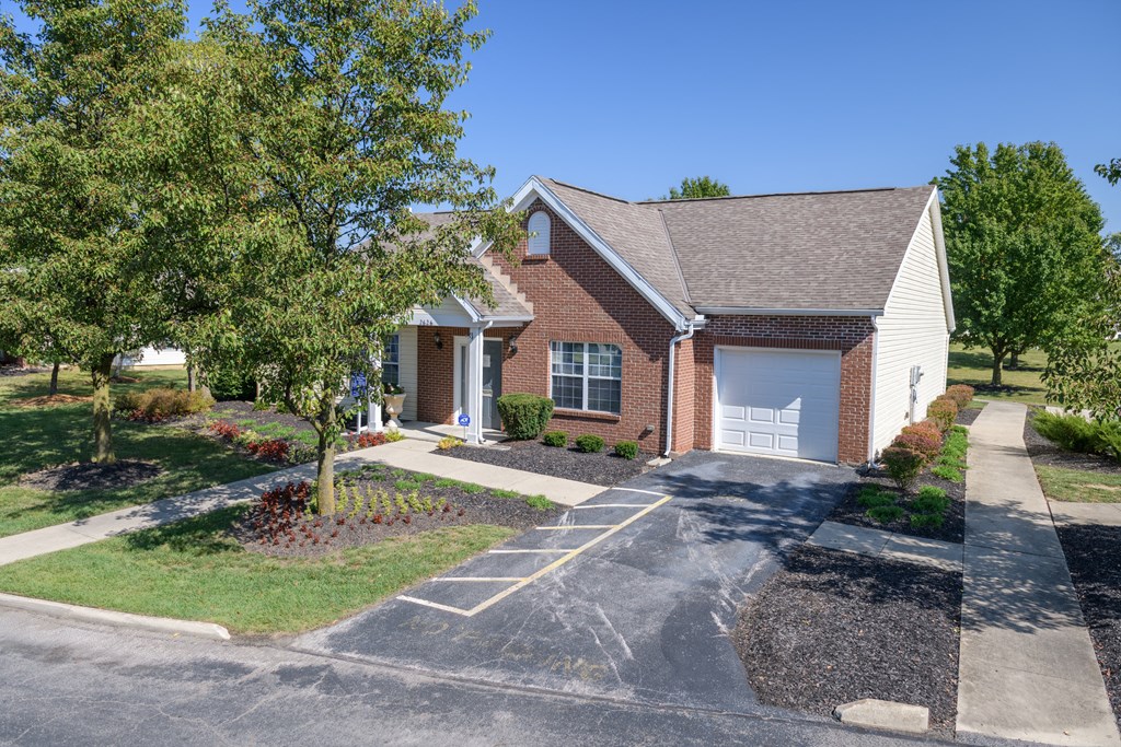 a red brick house with a white garage and trees