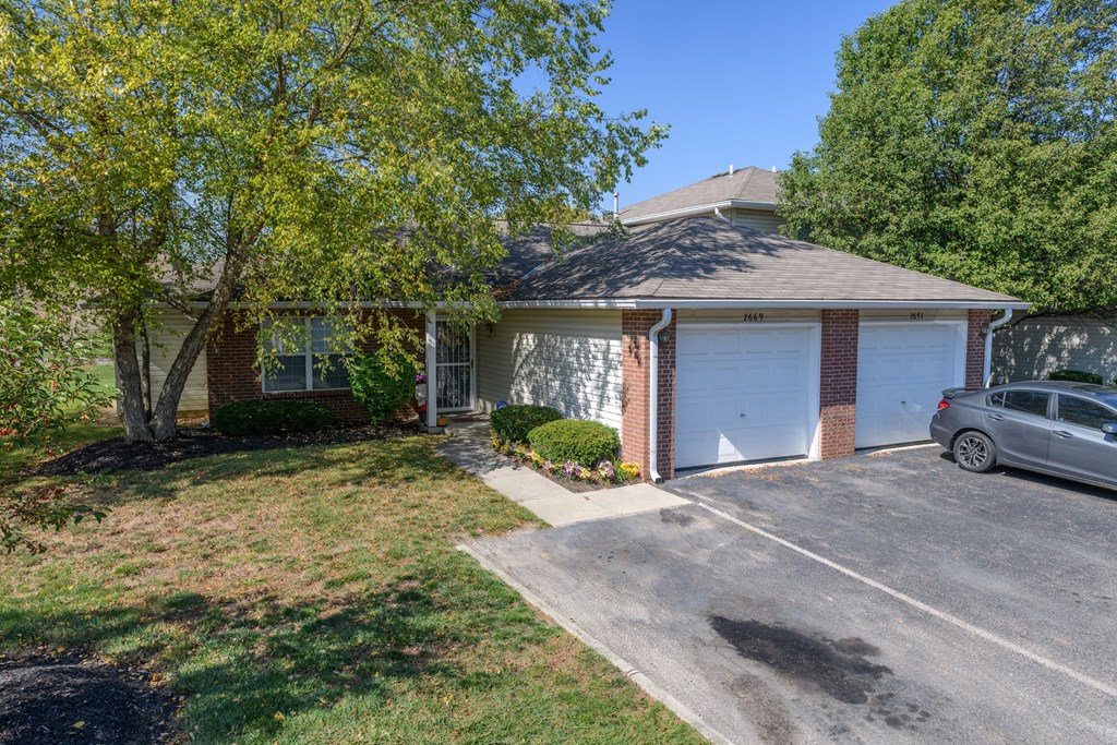 a small brick house with a car parked in the driveway