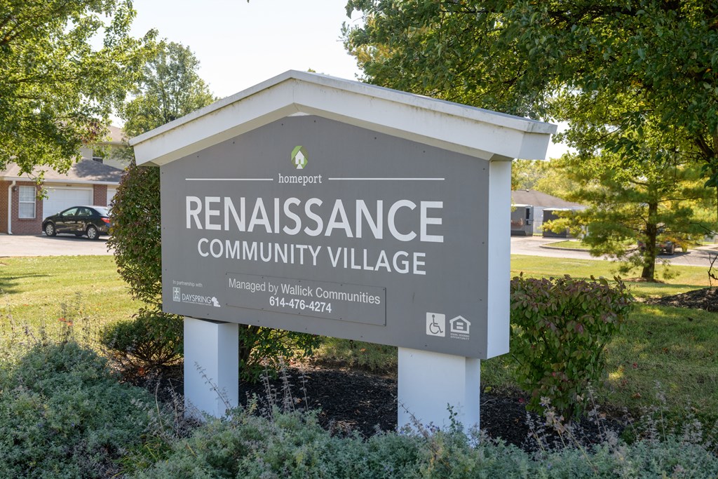 a sign for the renascence community village in front of a park