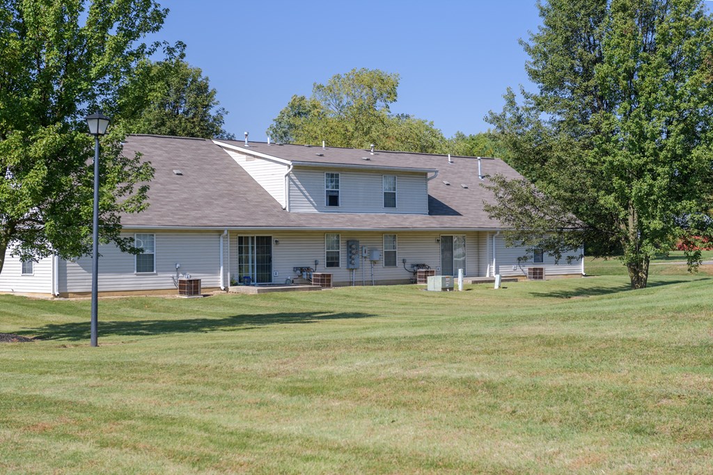 the front of a white house with a lawn and trees