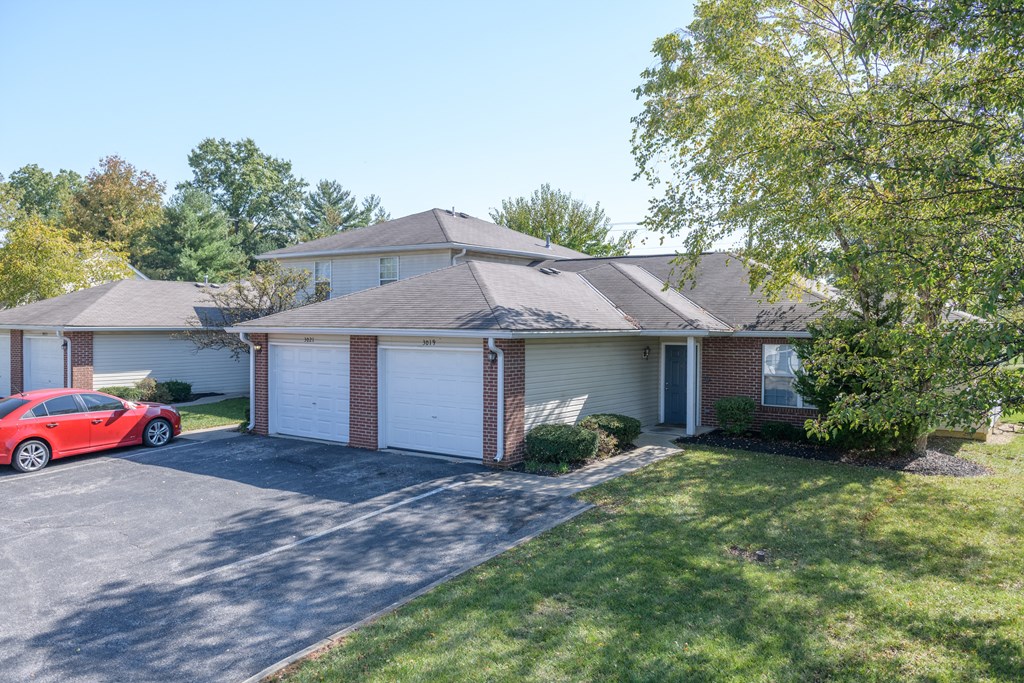 a white and brick house with a red car parked in the driveway
