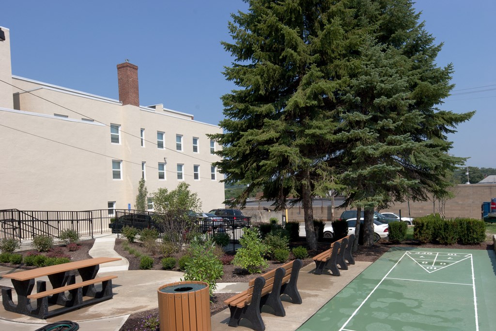 a basketball court and benches in a courtyard with a building in the background