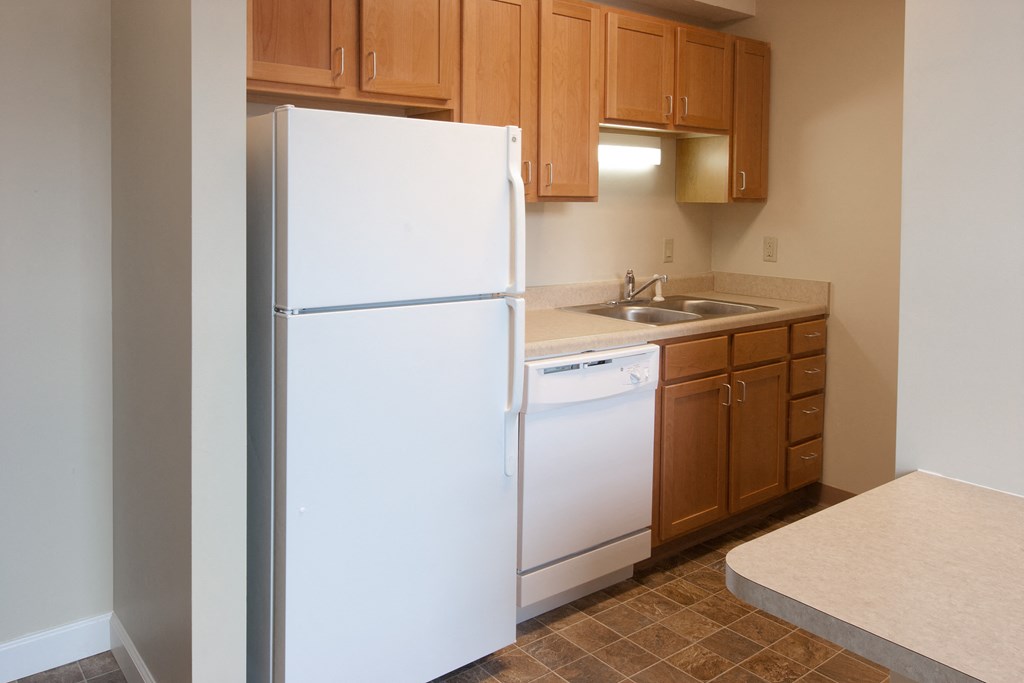 an empty kitchen with a white refrigerator and sink