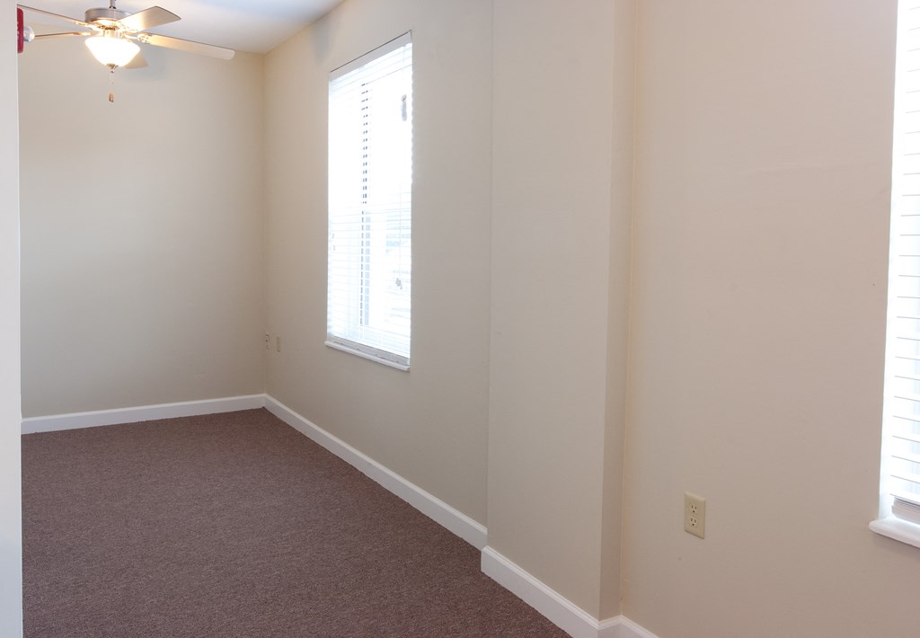 an empty room with a window and a ceiling fan