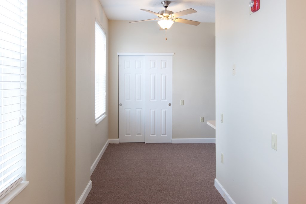 an empty bedroom with a ceiling fan and a door