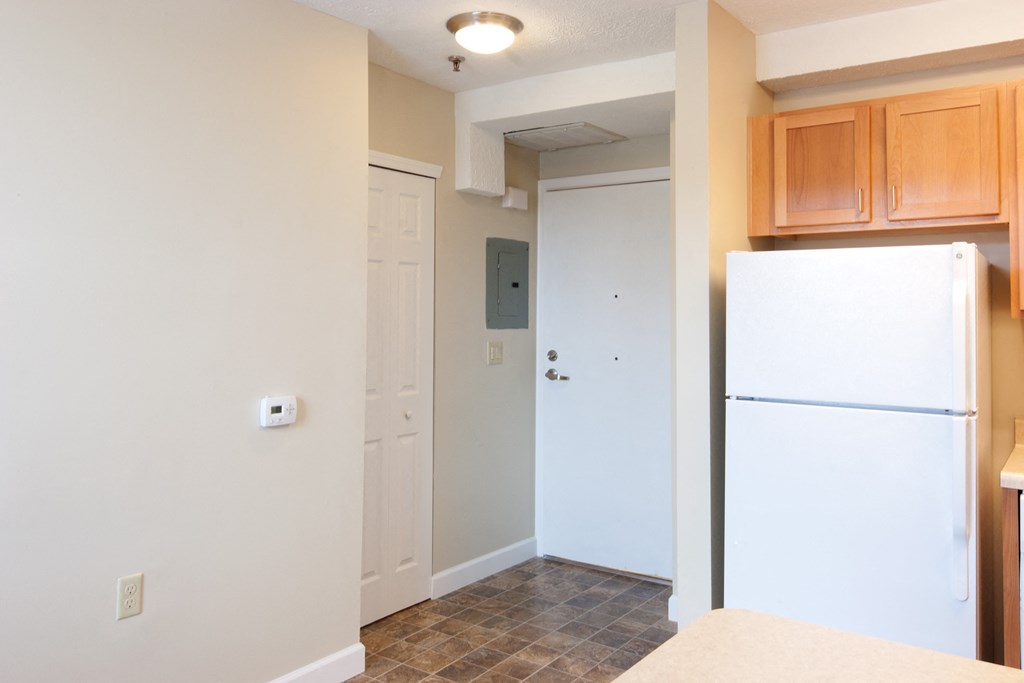 an empty kitchen with a white refrigerator and wooden cabinets