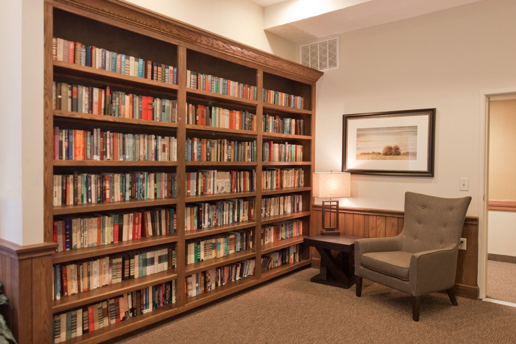 a library with a chair and a bookcase filled with books