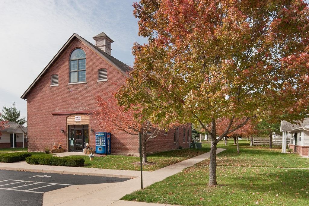 a red brick church with a sidewalk and trees in front of it