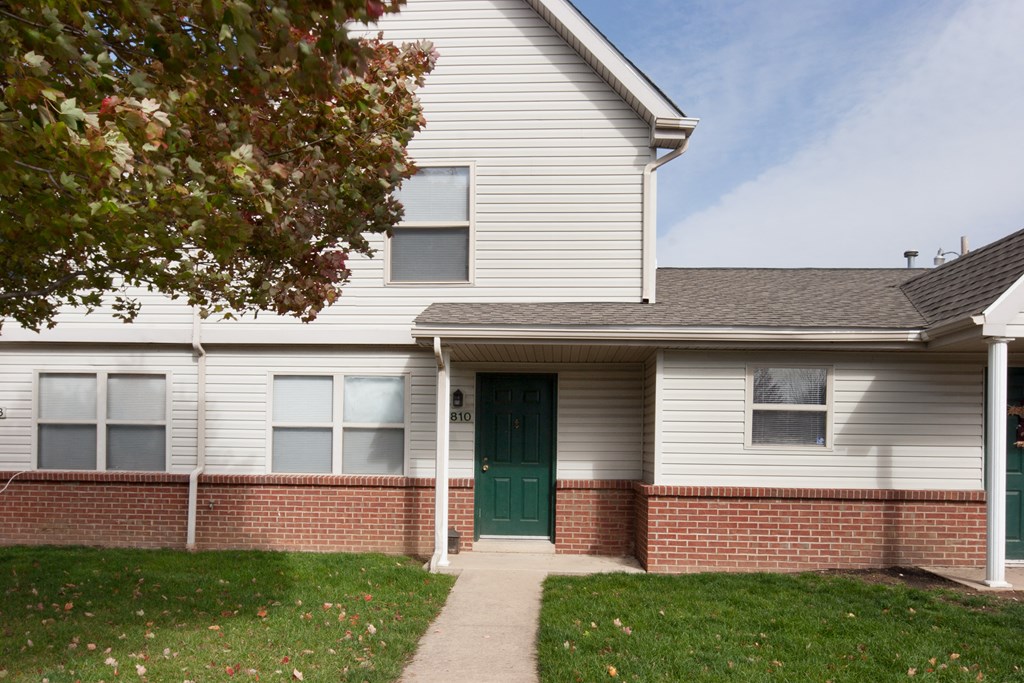 the front of a white house with a green door