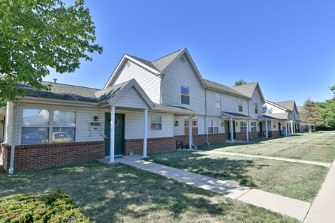 a row of white houses with a sidewalk and grass