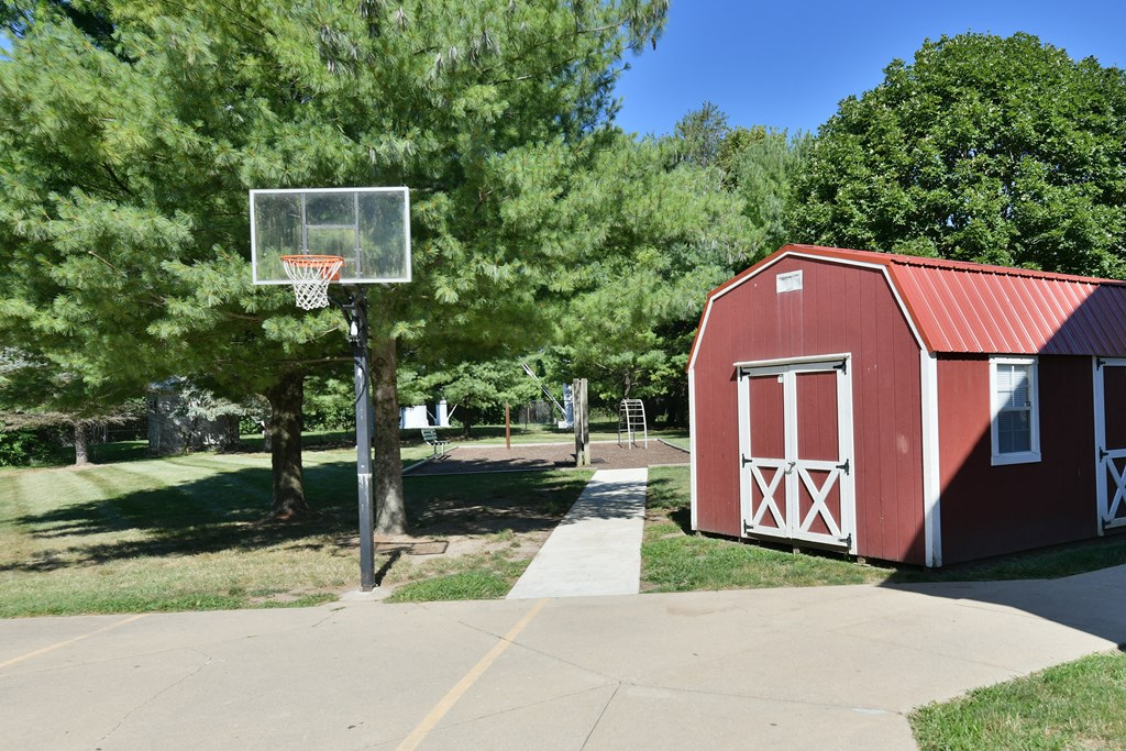 a red barn with a basketball hoop on the side of a driveway