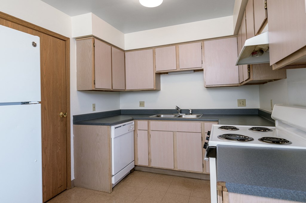 an empty kitchen with white appliances and wooden cabinets