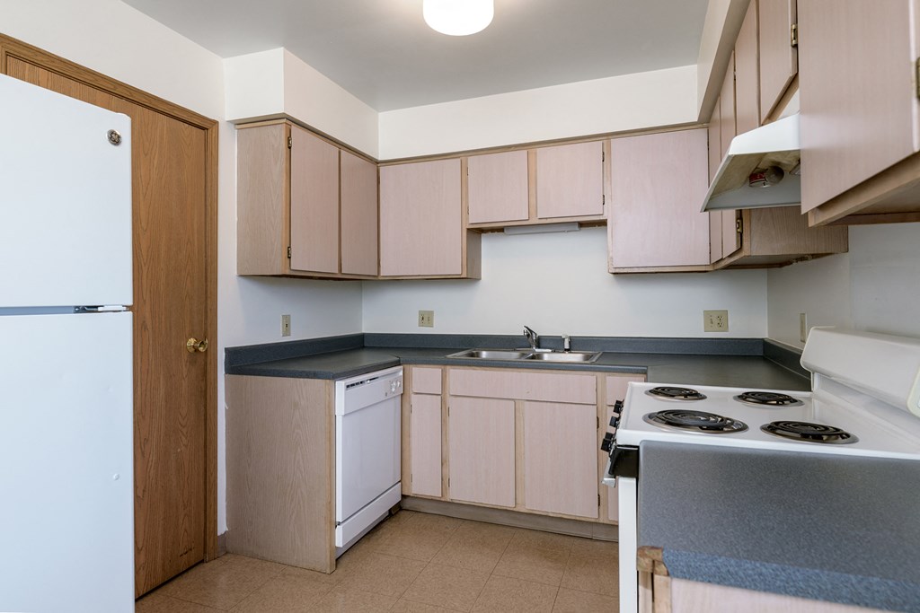 an empty kitchen with white appliances and wooden cabinets