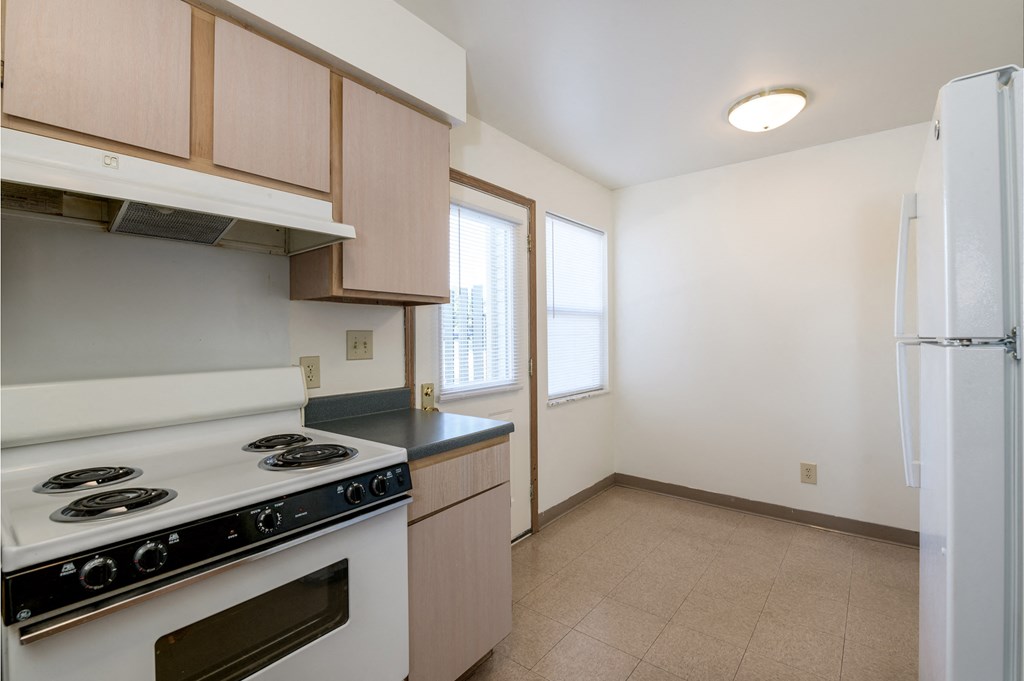 a kitchen with a stove and refrigerator and a window