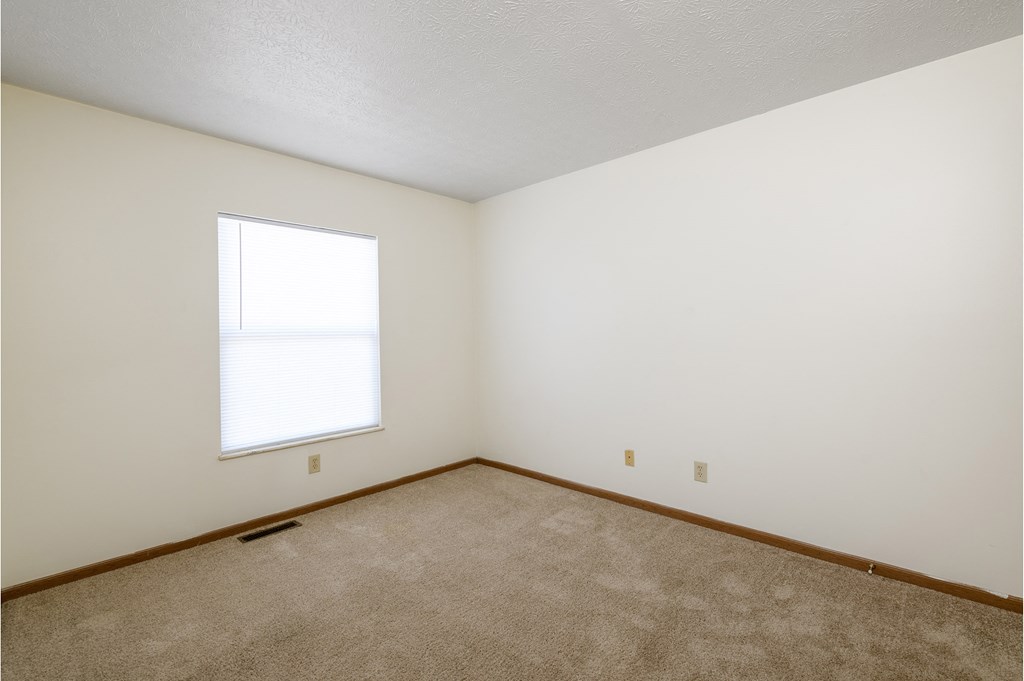 an empty room with a window and carpet