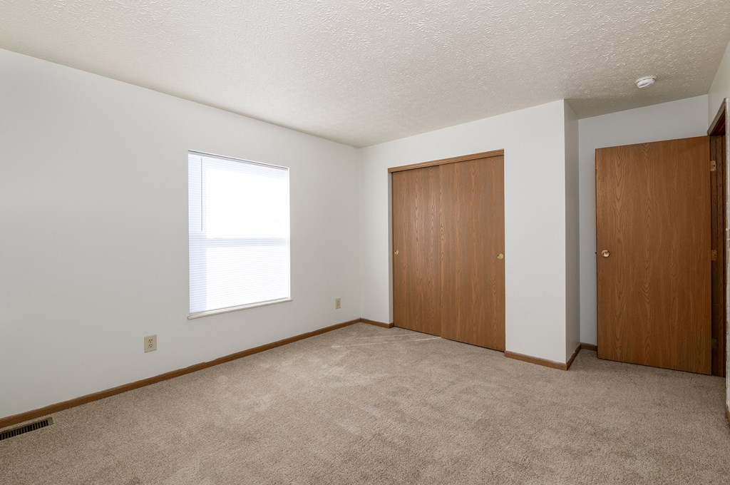 an empty living room with a door to a closet and a window