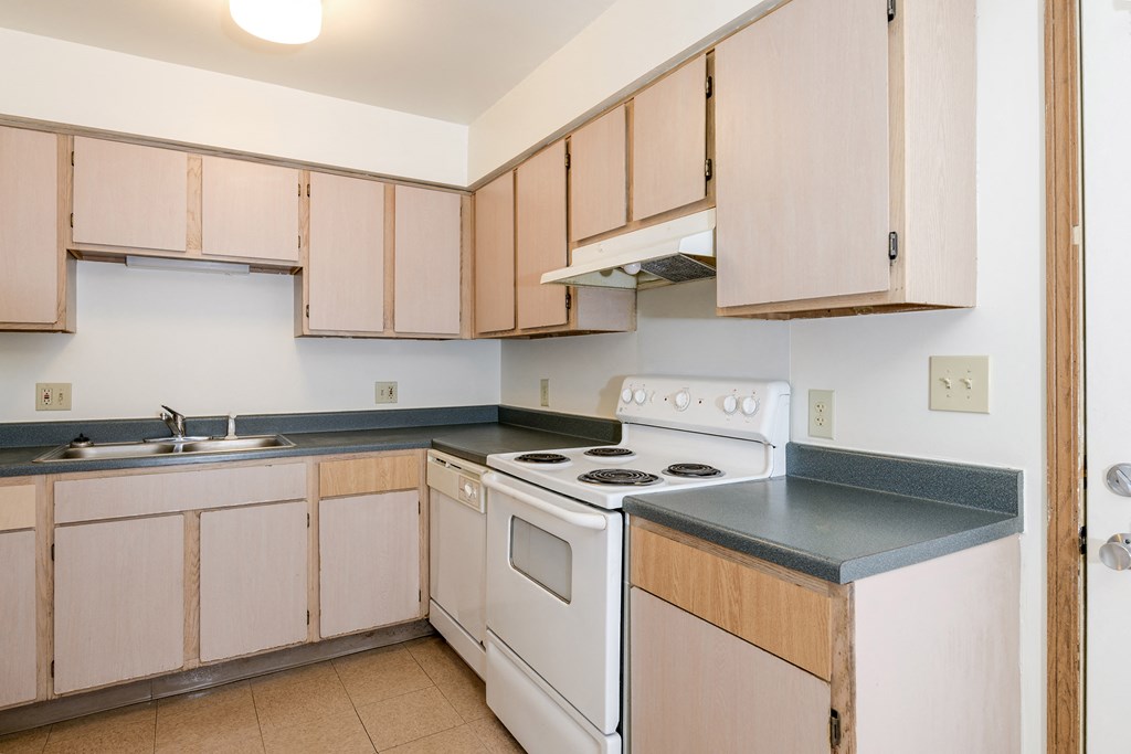 an empty kitchen with white appliances and wooden cabinets