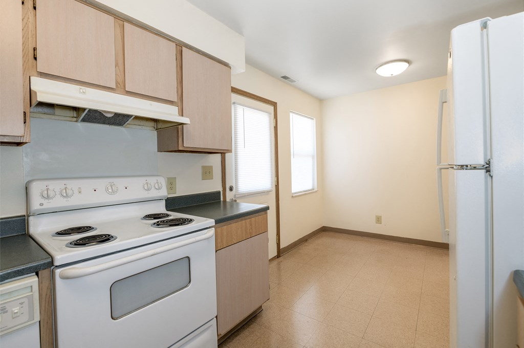 a kitchen with white appliances and wooden cabinets and a white refrigerator