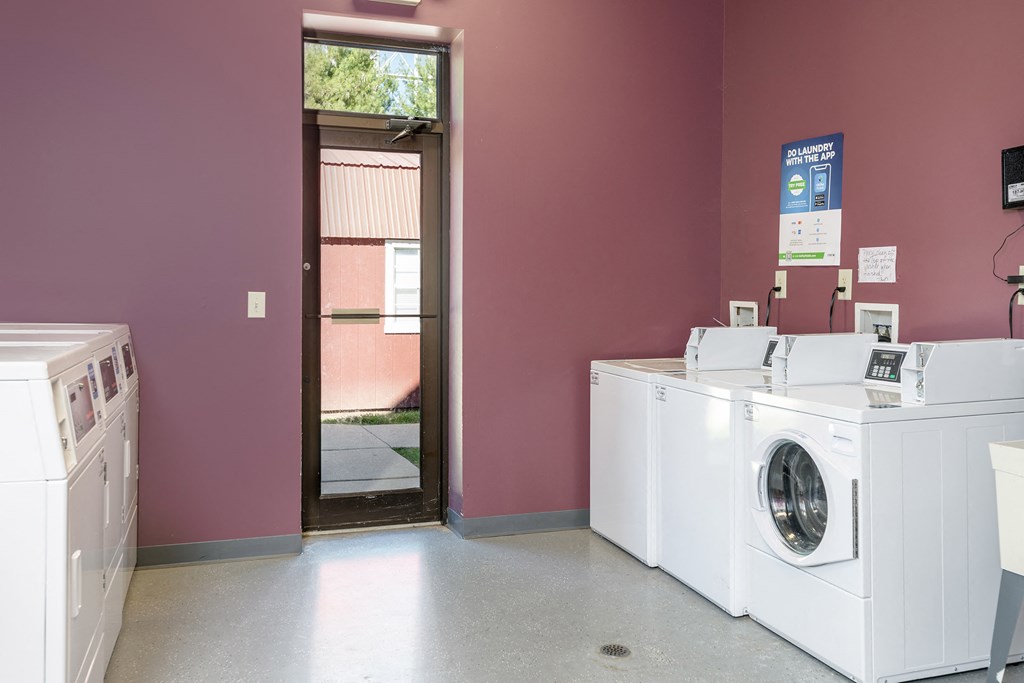 a laundry room with two washing machines and a door to a building