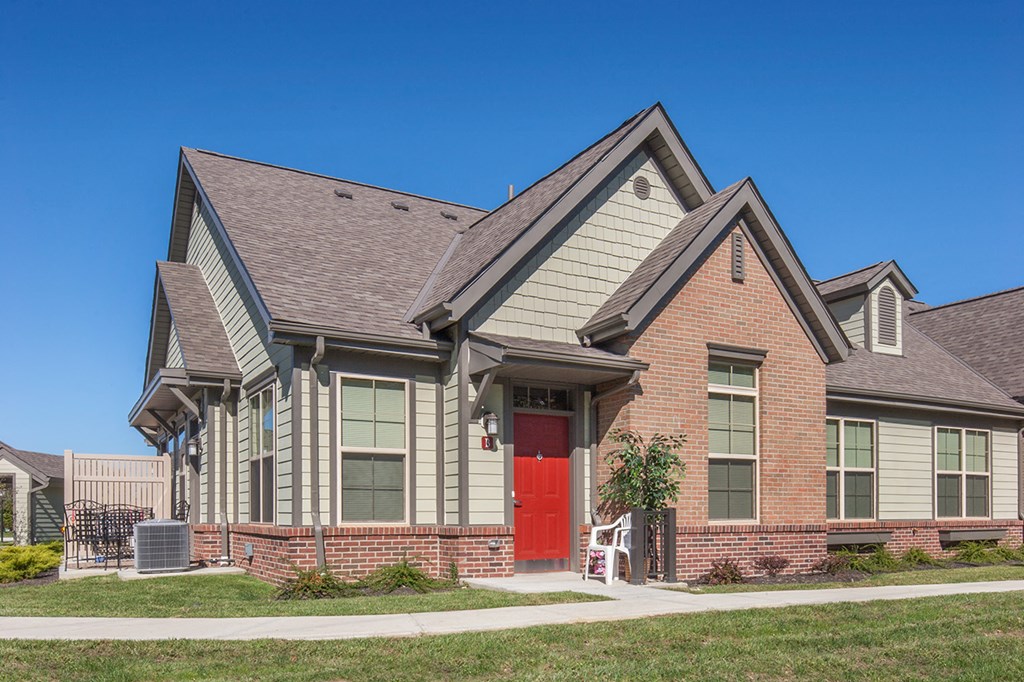 the front of a brick house with a red door