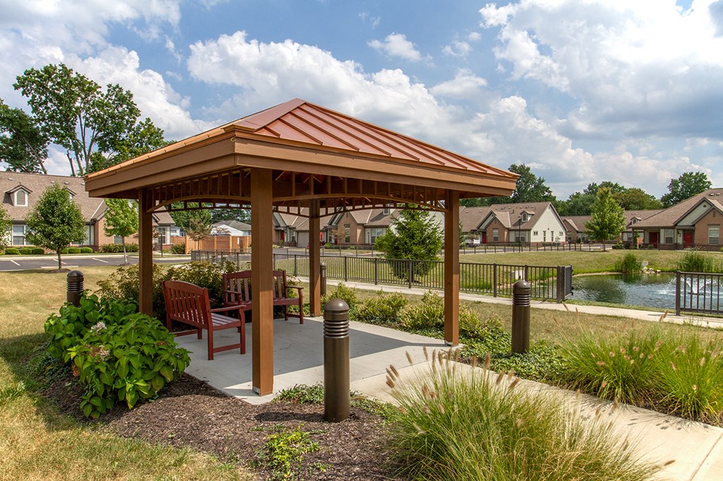 a pavilion with a table and chairs near a pond