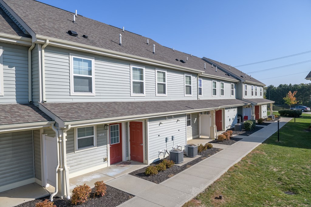 a row of white houses with red doors and a sidewalk
