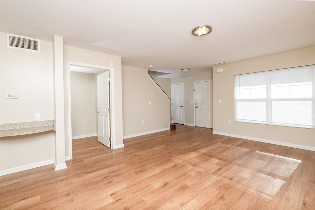an empty living room with wood floors and white walls