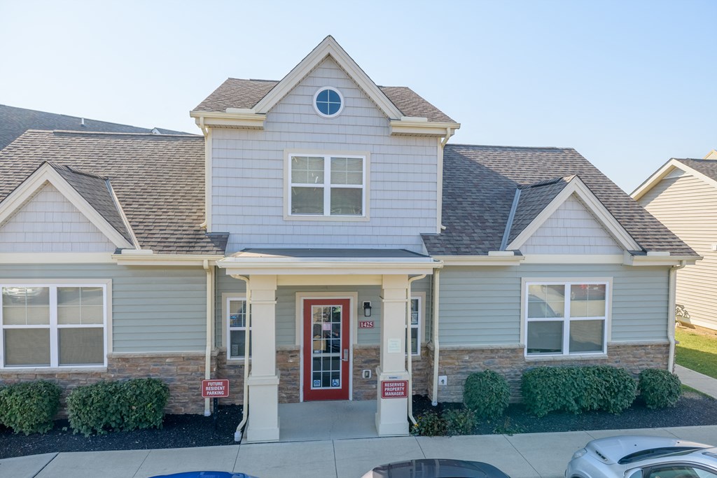 a white house with a red door and a parking lot