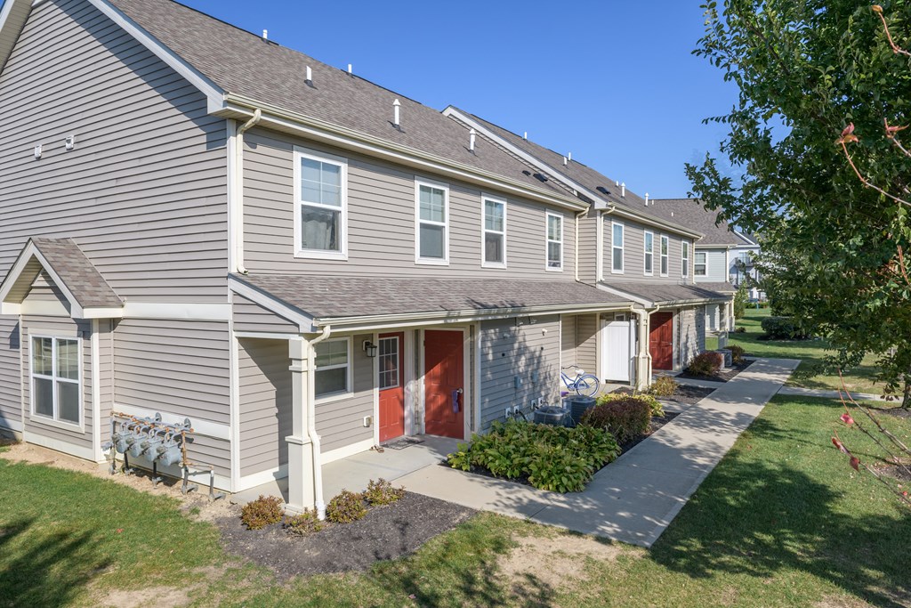 a row of houses with red doors and a sidewalk