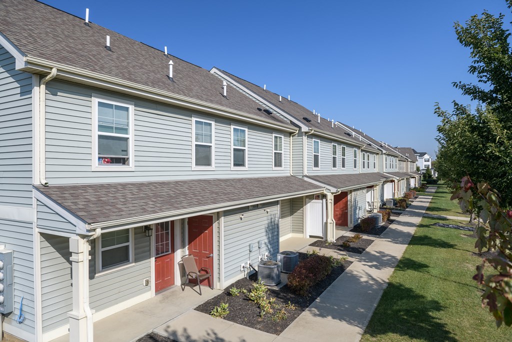 a row of white houses with red doors and a sidewalk